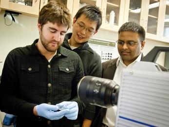 Kripa Varanasi, right, a professor of mechanical engineering, and graduate students Hyuk-Min Kwon, center, and Adam Paxson stand in front of the high-speed camera used to capture images of water droplets on a surface.