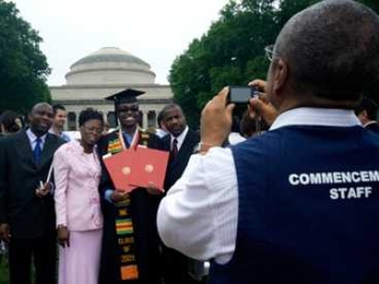 A Commencement volunteer takes a picture of a graduate and his family at the 2009 Commencement ceremonies.