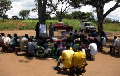 Amy Smith, in blue dress, leads a workshop in a village in Uganda.