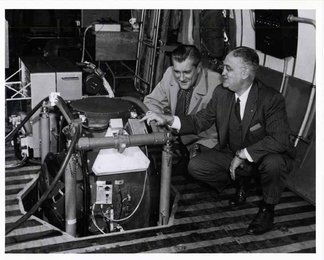 Charles Stark Draper, right, and CBS journalist Eric Sevareid take a look at the automatic navigation system developed by the MIT Instrumentation Laboratory. In 1958, Sevareid, Draper and several I-Lab staff members made a nationally televised cross-country flight piloted by the system. 