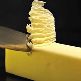 Sharp object skims off top of yellow block, forming a stack of soft residue.