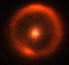 At the center of this infrared image is a massive red galaxy, 9.8 billion light-years from Earth, which acts like a cosmic magnifying glass, distorting the light from an even more distant galaxy. The observations were made with the 10-meter Keck-11 Telescope on Mauna Kea, Hawaii.