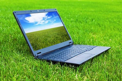 An open laptop sits on a patch of grass