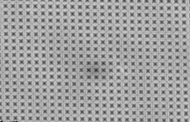 Seen from above, a sheet of silicon has been textured with an array of tiny inverted-pyramid shapes, so small that they correspond to the wavelengths of light and can efficiently trap light waves.