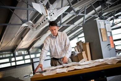 AeroAstro professor Olivier de Weck surveys aircraft blueprints in MIT's Neumann Hangar. With de Weck's new new approach, engineers may design airplanes to fly in the face of likely failures. 
