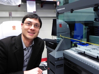 MIT Assistant Professor of Physics Jeff Gore in his lab with Tecan Freedom Evo pipetting robot that will be used to study evolution of cooperative behaviors in single-celled yeast.