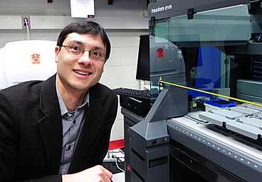 MIT Assistant Professor of Physics Jeff Gore in his lab with the Tecan Freedom Evo pipetting robot.
