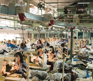 Photo of a factory floor, with many dozens of workers seated at sewing machines