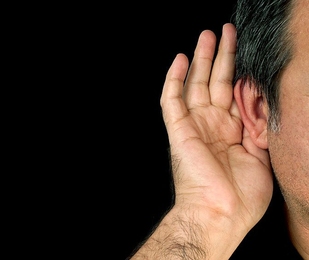 Human hand placed up against an ear
