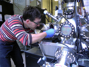 MIT Materials Science and Engineering graduate student Nicolas M. Aimon inserts a holder into a pulsed laser deposition chamber.