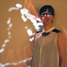 Architecture student Paloma Gonzalez Rojas standing in front of WalkAcross, her project that displays a real-time visualization of visitors' motion in the MIT Museum.