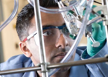 Man holding chemistry equipment up to look at it