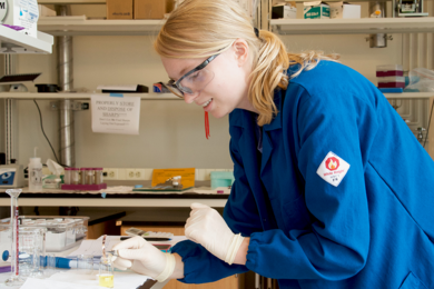 A woman in a lab wearing safety goggles