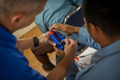 Explosive ordnance technicians work with 3-D printed models to learn how different unexploded shells and land mines work.