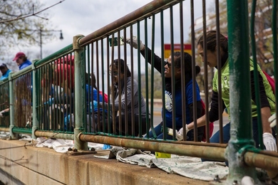 MIT community members paint a railing along roads near MIT's campus as part of the inaugural Together in Service Day, held on Tuesday, which included dozens of volunteer opportunities across the region and beyond. 