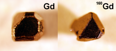 At left: A single crystal compound of gadolinium, platinum, and bismuth made with naturally occurring elements. At right, a single crystal of this material made with isotopically enriched gadolinium for neutron scattering experiments. Both crystals are approximately 1 mm in size. 