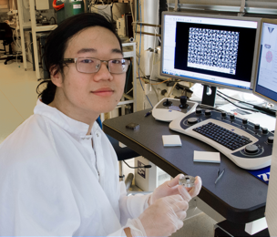 Summer Scholar Justin Cheng holds an experimental sample of nanostructured gold on silicon that has potential for use in sensors and display technologies based on its selective light absorption properties.