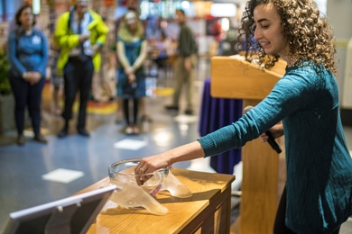 Grad student Juliana Philippa Kerrest drops a marble into the “Helping You, Helping Others” glass sculpture in the Student Center as a visible testament to personal experiences of help-seeking at MIT.
