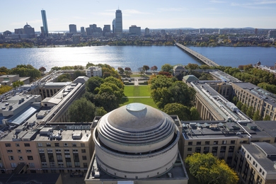 Drone photo of MIT's Great Dome with Charles River and Boston skyline behind it