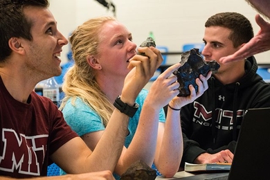 Space Systems Engineering students (left to right) Jeremy Stroming, Tori Wuthrich, and Nicholas James compare the properties of stony and iron meteorites.