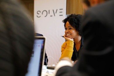 people at computers with "Solve" poster in the background