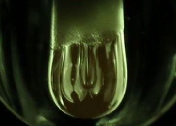 A molten hanging droplet, or pendant (at center), forms from an aluminum oxide rod under intense heat and light from xenon lamps. Using this process, MIT researchers have demonstrated a new electrochemical method to study thermodynamic processes in a molten oxide melt at temperatures above 2,000 degrees Celsius. 