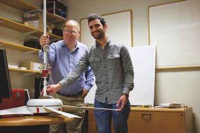 Professor James Kirtley Jr. (left) and Tata Fellow Mohammad Qasim hold a state-of-the-art ceiling fan that they use as a benchmark for evaluating the performance of their motor designs. A variety of instruments generate measurements they use to calculate how much of the power from the fan ends up actually moving air, determining the efficiency of the device.