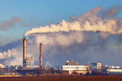Clouds of pollution float into the sky from two smoke stacks