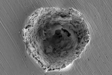 This scanning electron micrograph shows the crater left by the impact of a 10-micrometer particle traveling at more than 1 kilometer per second. Impacts at that speed produce some melting and erosion of the surface, as revealed by this research.