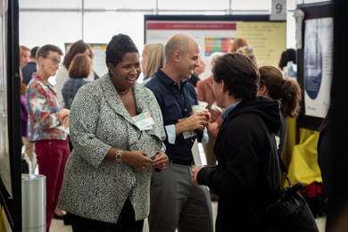 people smiling and talking in front of scientific posters