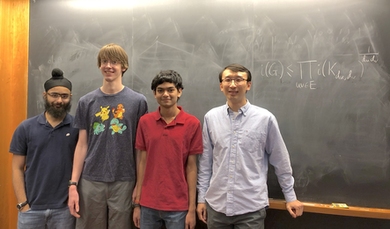 MIT Assistant Professor Yufei Zhao (far right) gave undergraduates (l-r) Mehtaab Sawhney, David Stoner, and Ashwin Sah a particularly vexing combinatorics problem. Their theorem on the number of independent sets in a graph is on the board behind them.