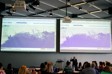 Professor John Sterman displays maps showing the consequences of sea-level rise on various coastal cities, as part of the “SimPlanet” event at MIT.