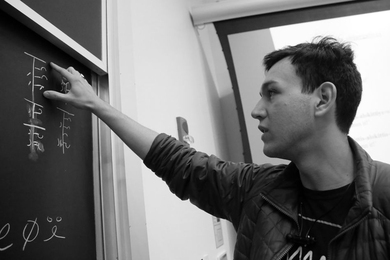 Junior Alex Cuellar with his constructed language. The chalkboard reads: "I can speak Oafal."