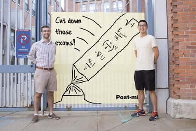 Nick Demas PhD '19 (left) and Jerry Wang PhD '19 stand outside Edgerton House with a larger-than-life note of encouragement.