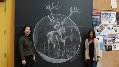Jessica Xu and Priscilla Wong stand in front of their finished chalk art in the Stata Center.