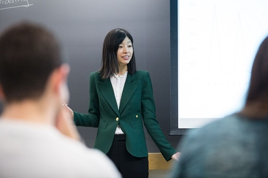 Jing Li, an assistant professor of applied economics, engages with her students during the Electricity Strategy Game debrief.