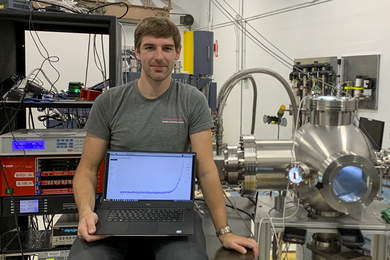 Photo of David Fischer in the lab, holding a laptop