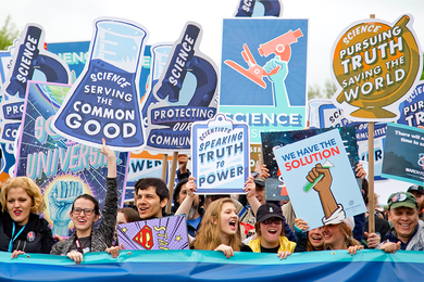 Photo from the March for Science in Washington D.C. showing at least a dozen smiling people with pro-science signs