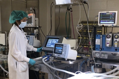 Photo of Shriya Srinivasan in a lab coat, conducting an experiment in lab