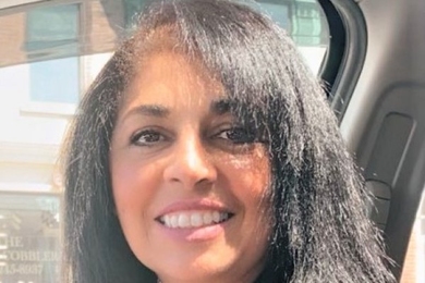 Photo of Lidia Vasconcelos sitting in a car and smiling