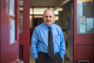 Photo of Robert Weinberg with hands in his pockets, standing in front of a red doorway