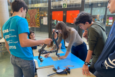 Photo of several students standing around a table with robot parts