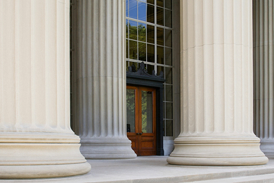 Photo of the entrance to MIT Building 10, which features several large columns in front of a double door