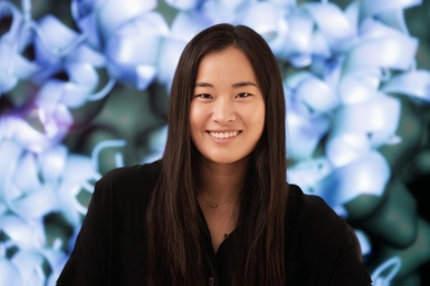 Portrait photo of Ellen Zhong smiling in front of a molecule mural