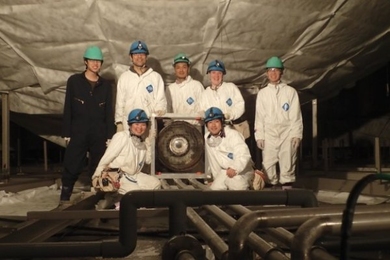 Photo of a group of students and professor posing with physics device