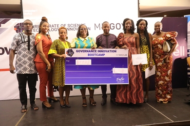 Photo of eight boot camp winners posing with a large prop cheque for $30,000