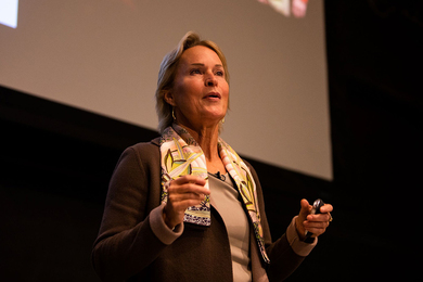 Closeup photo of Frances Arnold delivering a talk in front of a screen