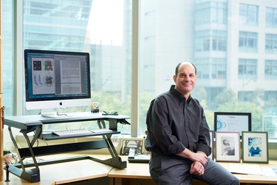 David Julius poses in his office, in front of a computer and framed photos