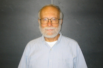 Headshot photo of Arthur Mattuck standing in front of a blackboard