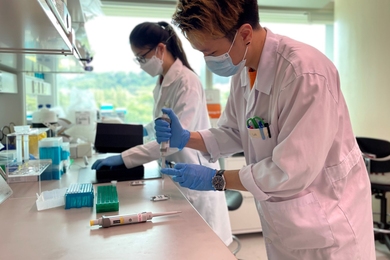 Photo of two white-coated researchers working over a lab bench.